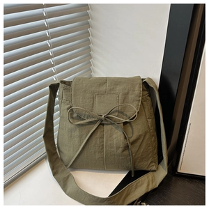 Detailed macro view of olive green messenger bag with nylon texture and bow detail