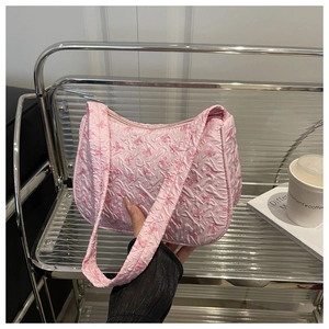 Detailed close-up of pink quilted underarm bag with cute dark pink bow patterns