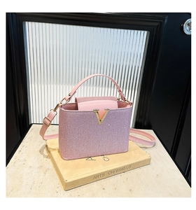 Detail of light pink sequin handbag featuring metallic V-logo and textured glitter finish