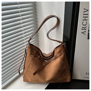 Detail view of caramel suede tote bag featuring decorative straps and metallic eyelets