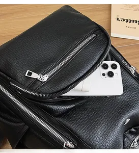 Detail of black faux crocodile leather backpack showing spacious front pocket with silver zipper