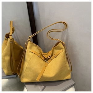 Detail view of yellow suede tote bag with adjustable shoulder strap and metal buckle