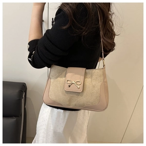 Close-up of beige shoulder bag with fabric texture and gold bow metal clasp