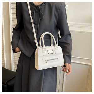 Close-up of white leather tote bag with silver zipper detail and adjustable strap