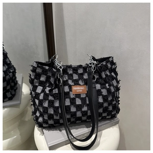 Detail of checkered tote bag featuring shaggy fabric texture and leather logo patch
