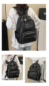Detail of black lychee grain leather backpack showing silver zippers and compartments