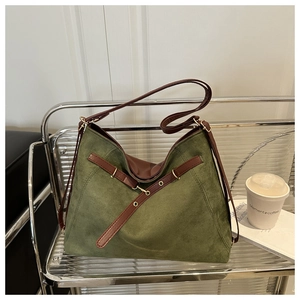 Detail of olive green suede tote bag with leather straps on a modern utility cart