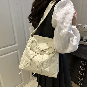 Cream nylon tote bag with bow detail and wide shoulder strap for women in casual style
