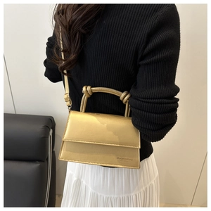 Detailed view of golden metallic small square bag with unique knot handle design