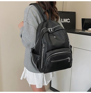 Close-up of a black waterproof leather backpack featuring durable silver metal zippers