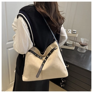 Detail of large tote bag showing black leather trim and triangle stitching on cream canvas