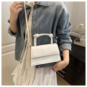 Close-up of white PU leather crossbody bag with knot handle and gold hardware details