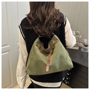 Detail of olive green suede tote bag with brown leather straps shown on a model
