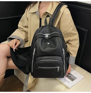 Close-up of black litchi grain leather backpack with metal zippers on a stylish model