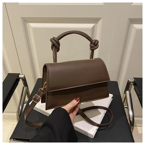 Close-up of chocolate brown PU leather bag featuring a thick knotted handle and flap design