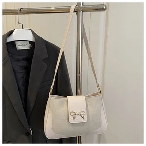 Close-up of cream sequin baguette bag featuring a decorative gold bow metal buckle