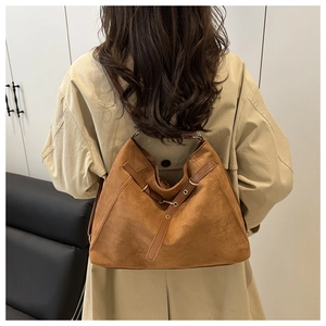 Detailed view of brown suede tote bag with leather straps and metal eyelet accents