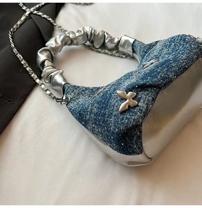 Détail du sac en denim et cuir argenté avec boucle papillon et poignée plissée nuage