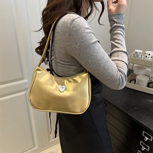 Metallic gold baguette shoulder bag with rhinestone heart bow on elegant model