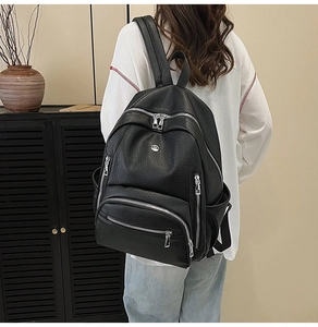 Rear view of model wearing black lychee texture leather backpack with silver zippers