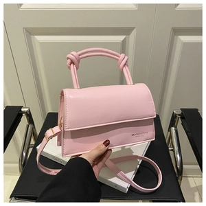 Detail of light pink crossbody bag featuring unique knotted handles and smooth leather texture