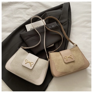 Detail of elegant beige and khaki suede handbags featuring gold bow metal buckles