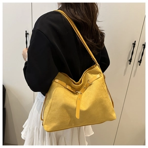 Close-up of a yellow matte leather tote bag with stylish criss-cross buckle detailing