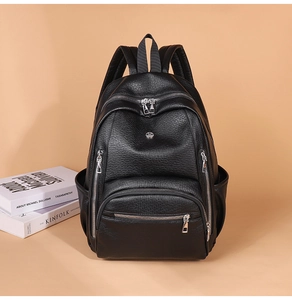 Close-up of black lychee grain leather backpack with silver zippers and side pocket detail