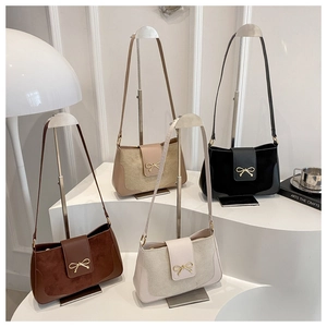 Detail showing four colors of minimalist suede and leather crossbody bags with golden bows