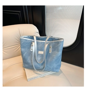 Dettaglio della borsa tote in denim azzurro con manici argentati e rivetti di rinforzo