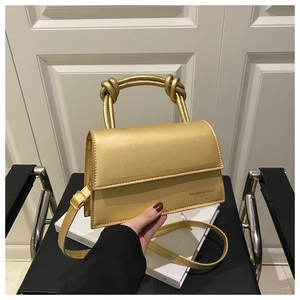 Detail of champagne gold square handbag with knotted handle and fine leather texture