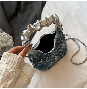 Détail du sac en jean avec ornement papillon en métal argenté et accents de paillettes