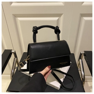 Detail of black crossbody bag featuring a knotted handle and gold metal hardware