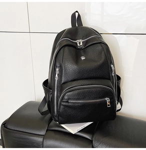Detailed close-up of a black lychee texture backpack with silver zippers on a bench