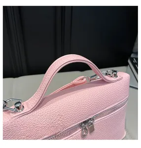 Detail of pink lychee leather handle and silver metal zipper on a small square bag