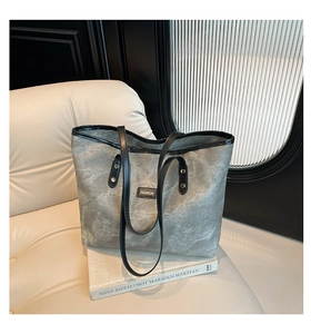 Dettaglio della borsa tote in tela grigia con finiture in pelle nera e logo Fashion