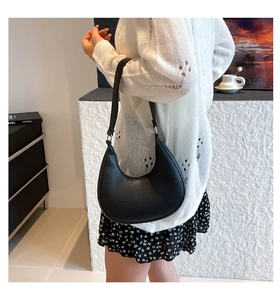 Detail of black lychee grain leather hobo bag with smooth silhouette and gold hardware