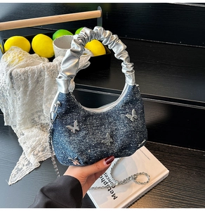Detail of denim crossbody bag with silver butterfly charms and sequin glitter texture