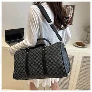 Detailed view of the large travel bag with grey M-pattern monogram and sturdy strap