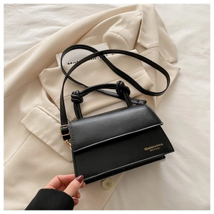 Detail of black leather handbag with knotted handle and gold embossed logo lettering