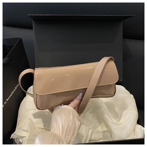 Gros plan d'un sac baguette en cuir verni beige brillant dans son coffret cadeau noir