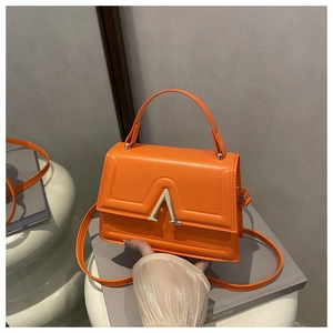 Detailed close-up of bright orange crossbody bag with silver V-shaped metal hardware