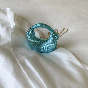 Close-up of bright blue metallic dumpling bag with pleated texture and gold chain strap