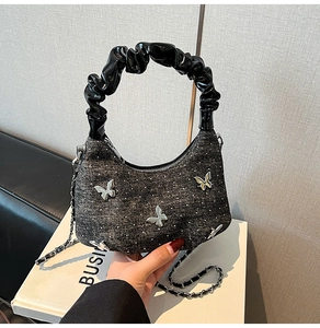 Detail of denim hobo bag with sparkling rhinestones and metallic butterfly accents
