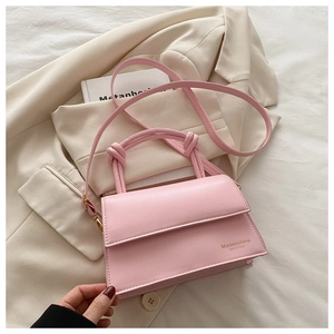 Detail of pink faux leather handbag with knot handles and embossed logo text design