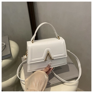 Close-up of a white leather crossbody bag with a signature golden A-shaped metal clasp