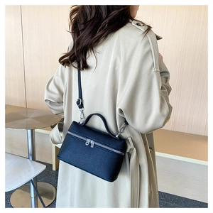 Detail view of black pebble leather crossbody bag with silver hardware on a model