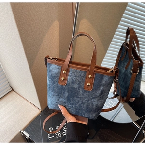 Detail der Bucket Bag aus gewaschenem Denim mit braunem Lederbesatz und Goldnieten