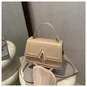 Detail of beige crossbody bag with premium gold V-shaped metal buckle and smooth texture