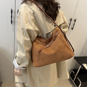 Brown suede tote bag with leather straps and metal rings shown on a model